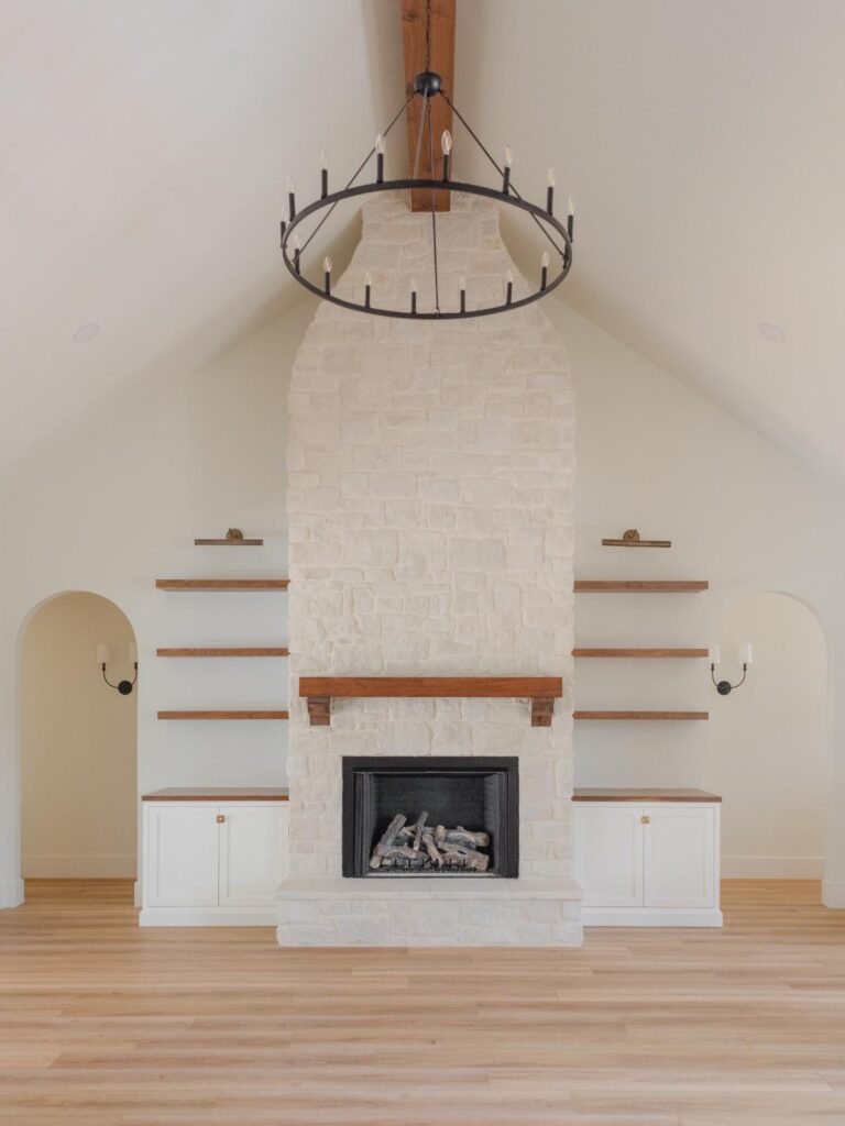 great room with tall ceilings, stone fireplaces, and wood beams 