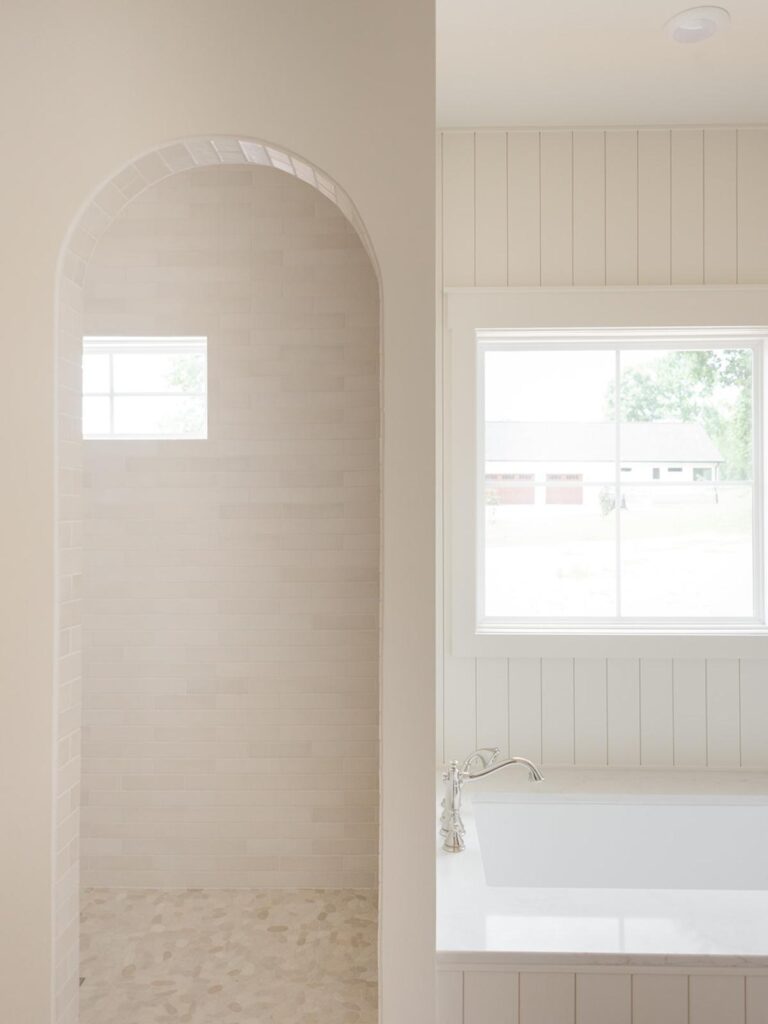 master bathroom with drop in tub and arched shower entry 